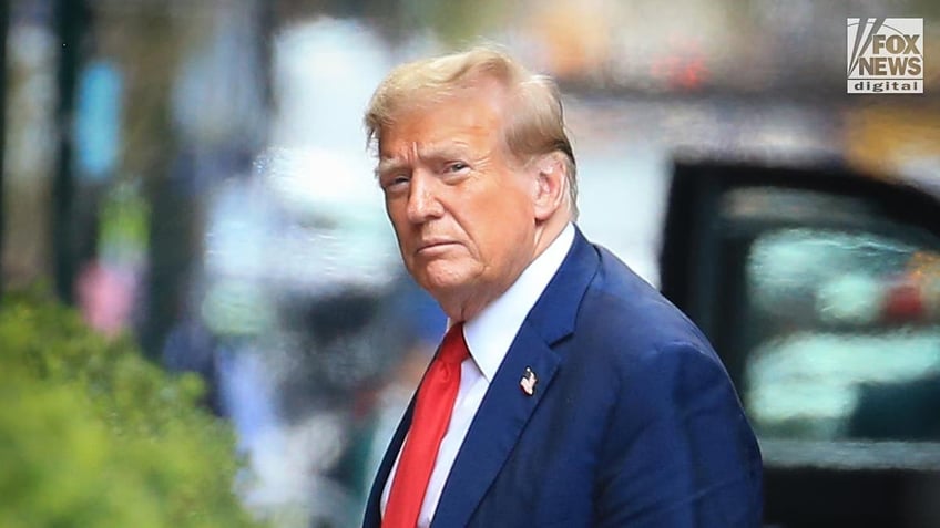 Trump looks at the camera, dressed in a blue suit and red tie.