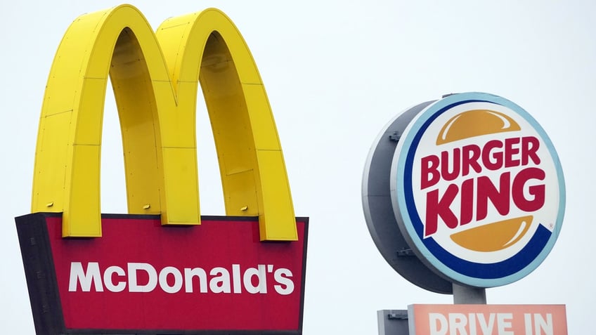 The logos of McDonald's as well as Burger King stand next to the respective fast food restaurants at a highway rest stop.