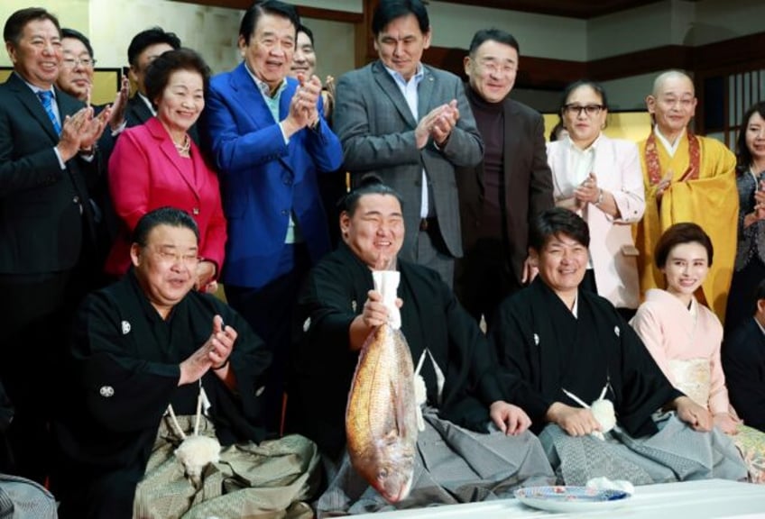 Sumo wrestler Hoshoryu holds a fish to celebrate being promoted to the sport's highest ran