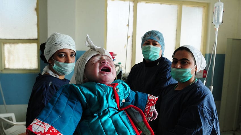 Afghan nurses hold a newborn boy after delivery in the maternity ward of a hospital as he was born on the auspicious "12.12.12" date in Mazar-i-Sharif on Dec. 12, 2012.