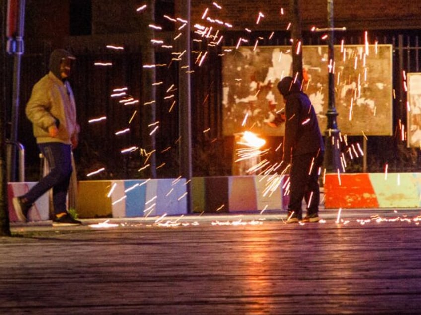 A man lights a small firework at the Kuregem/ Cureghem district of the Brussels municipali