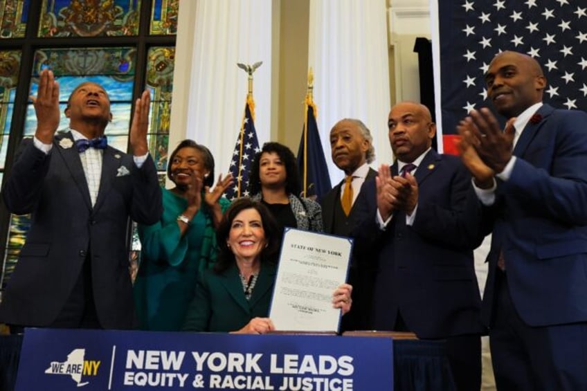 New York Governor Kathy Hochul holds up signed legislation creating a commission for the study of reparations in New York on December 19, 2023 in New York City