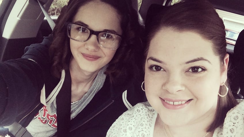 Bianca Devins leaning on her mother Kim Devins inside the car.