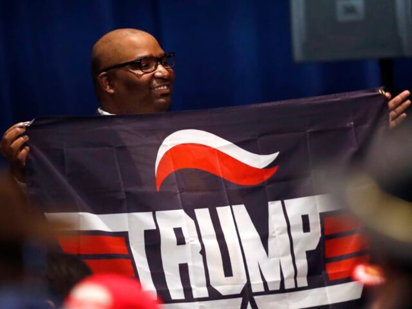 A supporter of President Donald Trump holds a Trump campaign banner as he waits for Trump