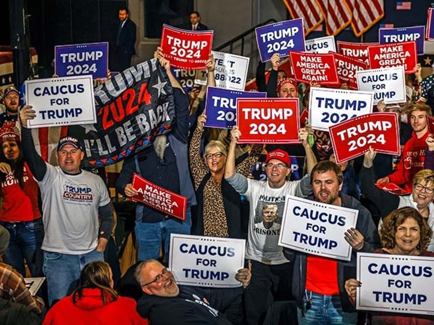 Supporters hold signs in front of TV cameras as they wait the arrival of former US President and Republican presidential hopeful Donald Trump speaks during a "Commit to Caucus" rally in Clinton, Iowa, on January 6, 2024. (Photo by TANNEN MAURY / AFP) (Photo by TANNEN MAURY/AFP via Getty Images)