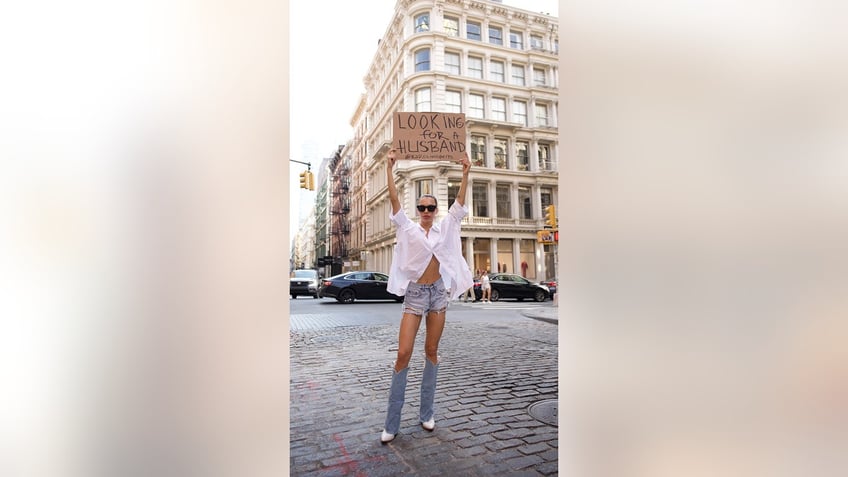 new york woman walks down the street with a looking for a husband sign sparking plenty of conversation