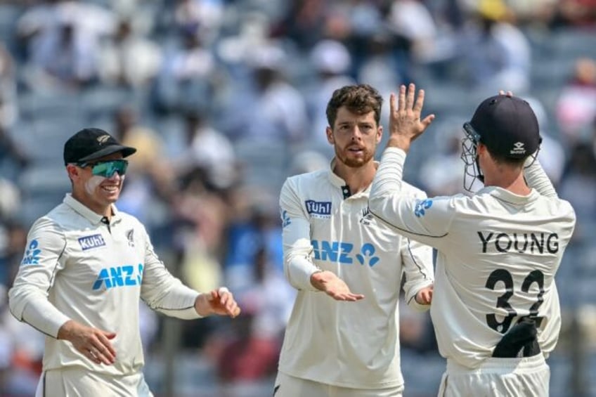 New Zealand's Mitchell Santner (C) celebrates with teammates after taking the wicket of In