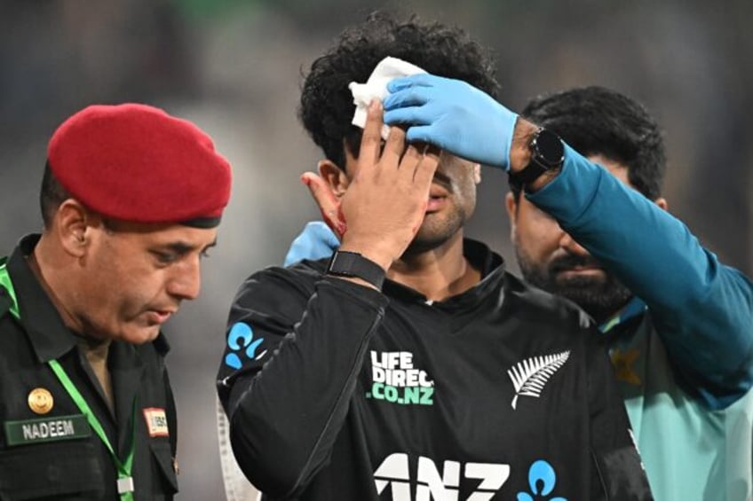New Zealand's Rachin Ravindra leaves the field after being hit on the head by the ball