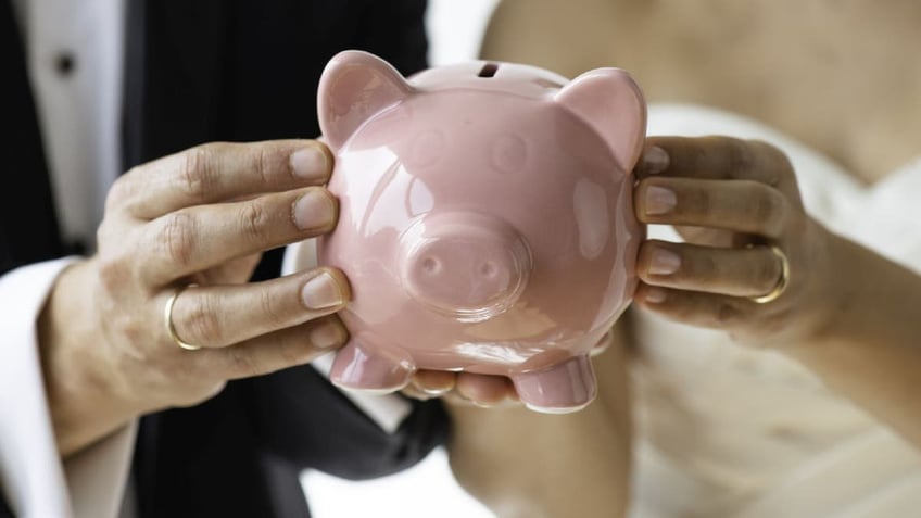 Bride and groom hold pink piggybank