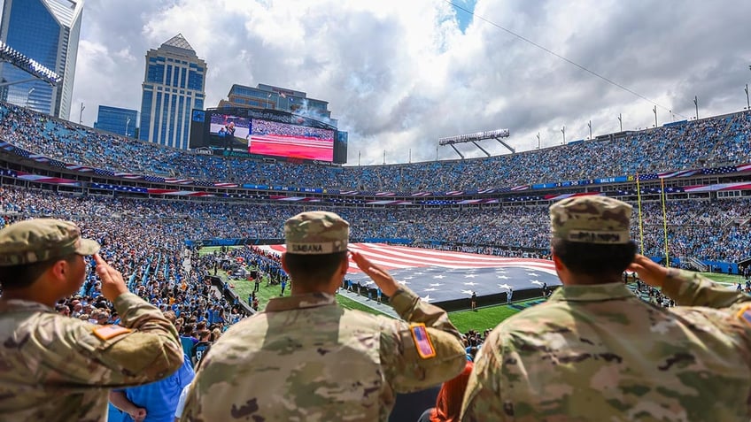 Army members salute at NFL game