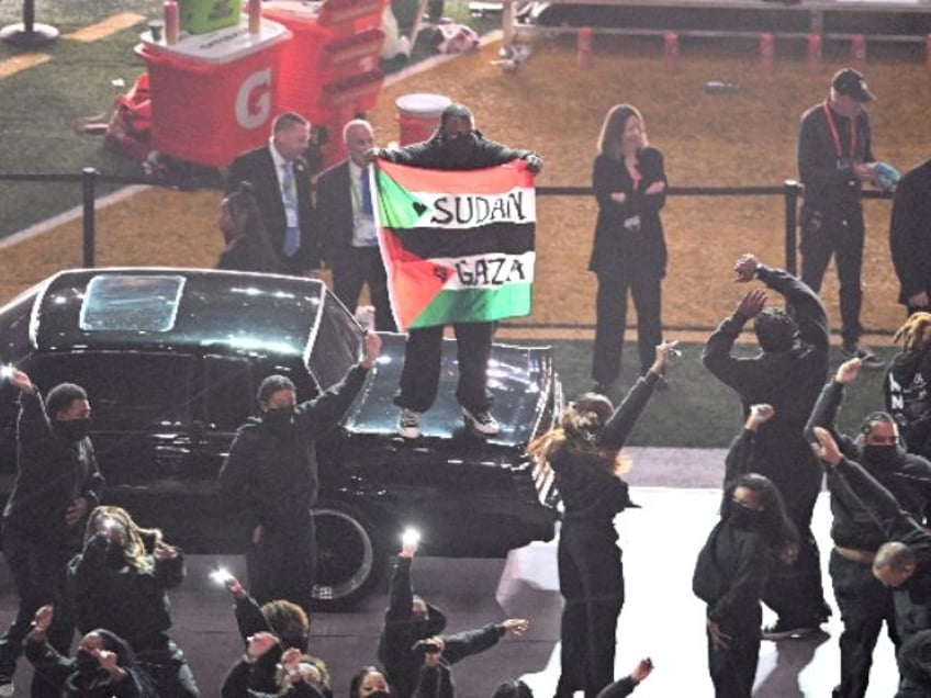 A protestor holds a Palestinian flag with the words "Gaza" and "Sudan"