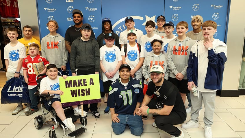 Tristian Wirfs, Jahmyr Gibbs and Cam Skattebo smile with kids