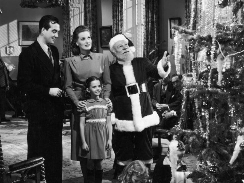 L-R: Actors John Payne, Maureen O'Hara, Edmund Gwenn (dressed as Santa Claus), and young Natalie Wood stand before a Christmas tree in a still from director George Seaton's film, 'Miracle on 34th Street.' (Photo by Hulton Archive/Getty Images)