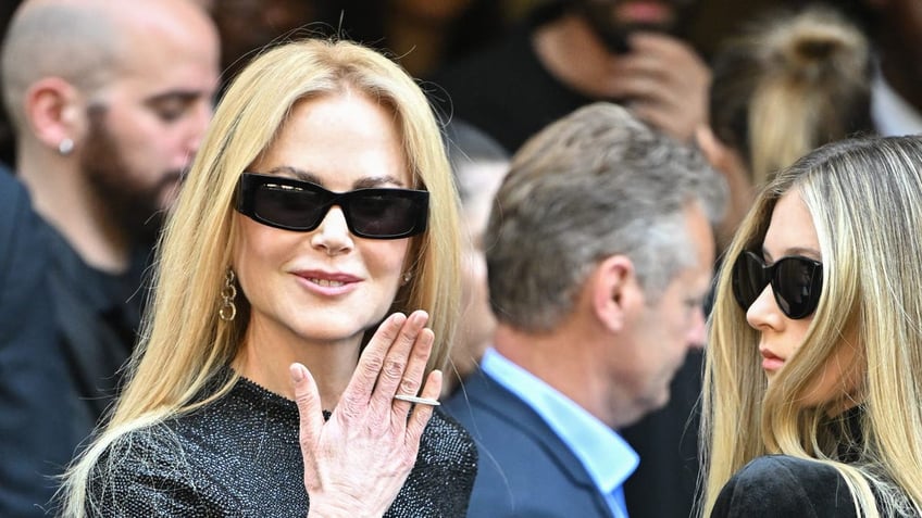 nicole kidman with her hand raised next to sunday rose