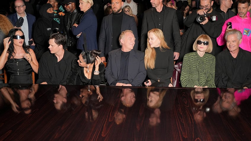 Katy Perry, Bill Skarsgård, Salma Hayek, François-Henri Pinault, Nicole Kidman, Anna Wintour and Kyle MacLachlan sit and converse at the Balenciaga fashion show, with Salma Hayek leaning towards Katy Perry and François having a conversation with Nicole