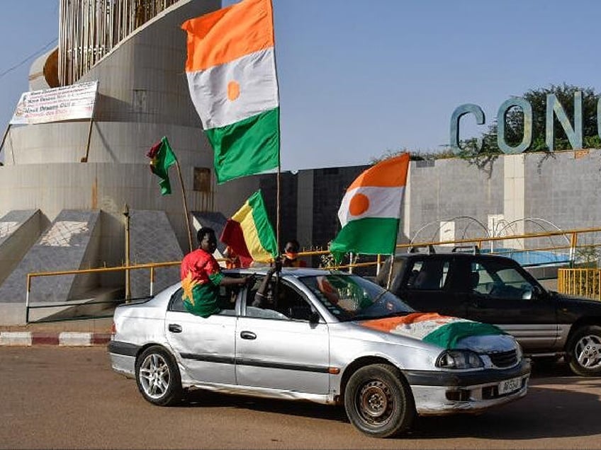 TOPSHOT - Supporters of the Alliance Of Sahel States (AES) drive with flags as they celebrate Mali, Burkina Faso and Niger leaving the Economic Community of West African States (ECOWAS) in Niamey on January 28, 2024. (Photo by HAMA BOUREIMA / AFP) (Photo by HAMA BOUREIMA/AFP via Getty Images)