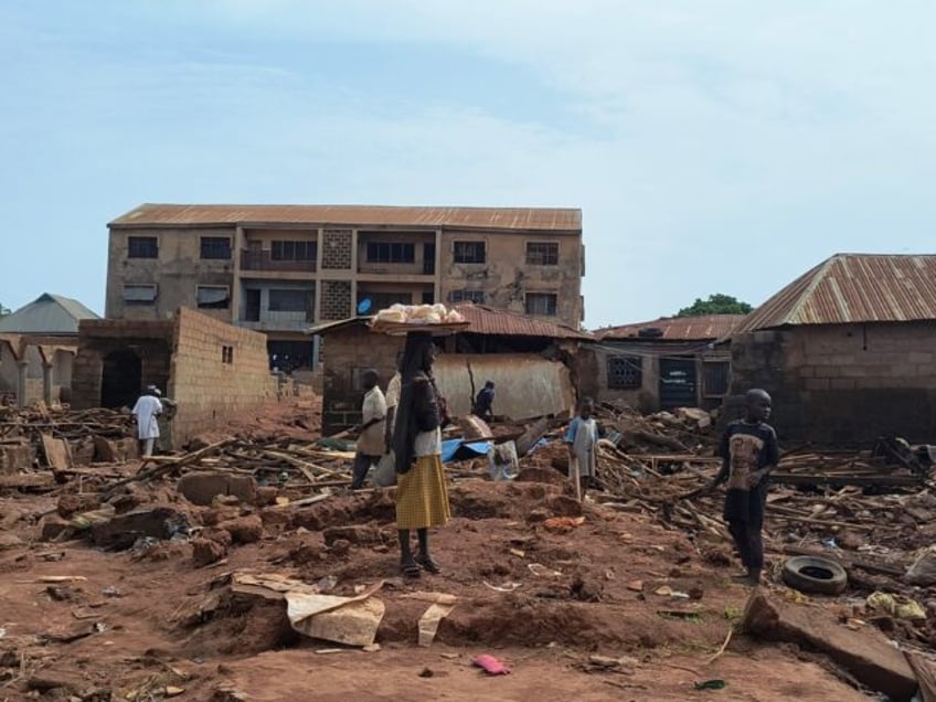 A woman stands next to debris from damaged buildings in Mokwa, Nigeria, where many bodies