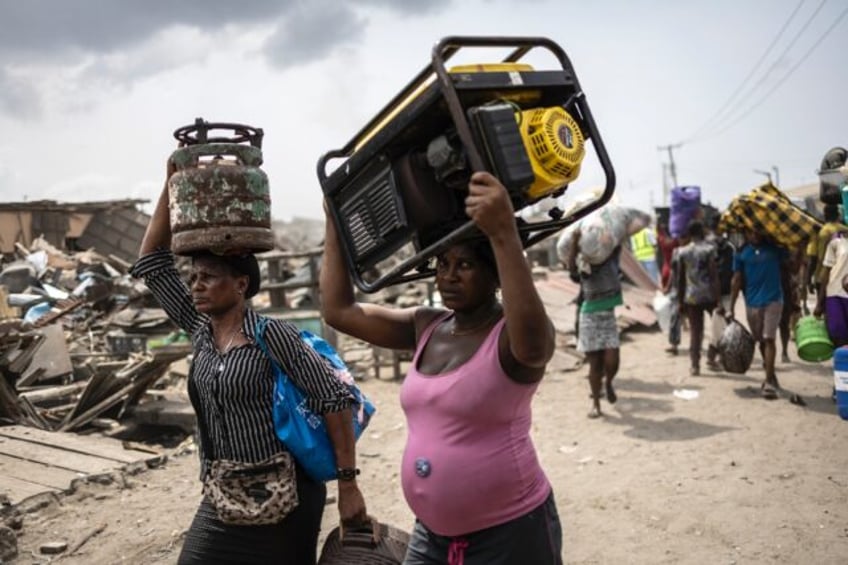 Residents carry their belongings as authorities demolish their homes in the working-class