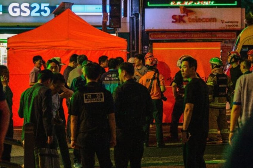 Emergency workers in Seoul stand near the site of a car accident which left at least nine