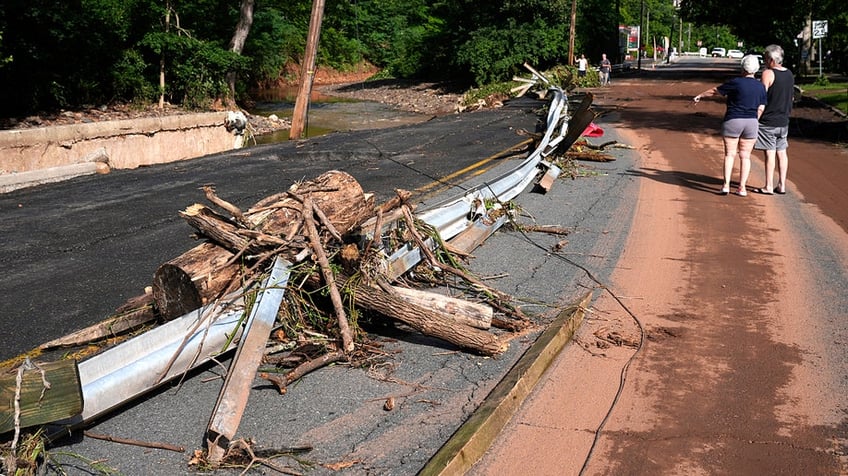 People on the side of the road observing damage after a flood