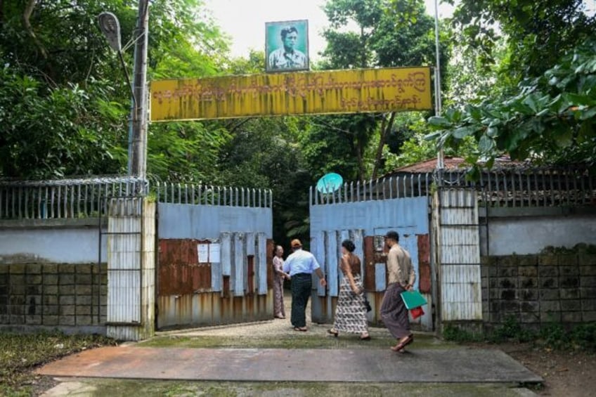 Auction officials walk through the gates of the family house of detained Myanmar civilian