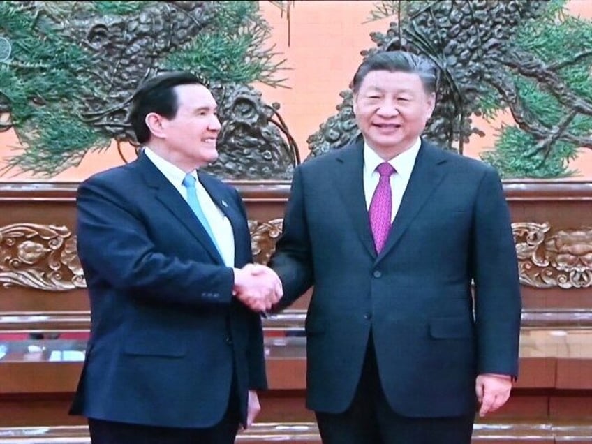 A screen shows news coverage of Chinese President Xi Jinping (R) meeting former Taiwan pre