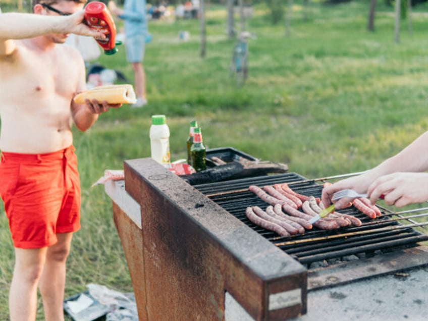 A man puts ketchup on his hotdog at a cookout.