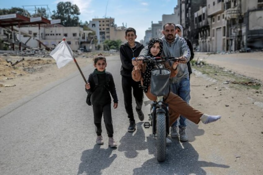 A girl holds a white flag as a displaced Palestinian family walks in Gaza City, in the ter