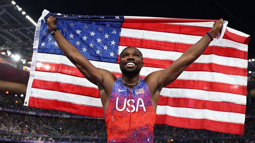 Noah Lyles holds an American flag