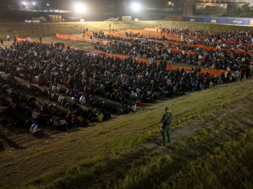 A U.S. Border Patrol agent watches over more than 2,000 migrants at a field processing center on December 18, 2023 in Eagle Pass, Texas. A surge as many as 12,000 immigrants per day crossing the U.S. southern border has overwhelmed U.S. immigration authorities in recent weeks. (Photo by John Moore/Getty Images)