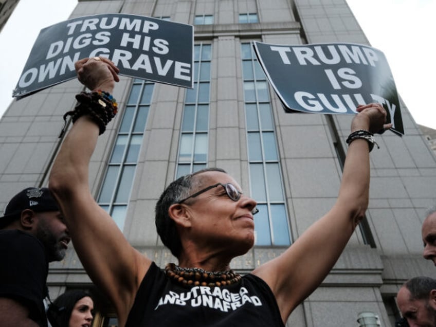 NEW YORK, NEW YORK - MAY 09: A protester holds up signs moments before writer E. Jean Carroll leaves a Manhattan court house after a jury found former President Donald Trump liable for sexually abusing her in a Manhattan department store in the 1990's on May 09, 2023 in New …