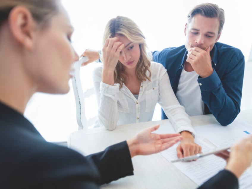 Real estate agent with couple looking through documents. The agent is holding a digital ta