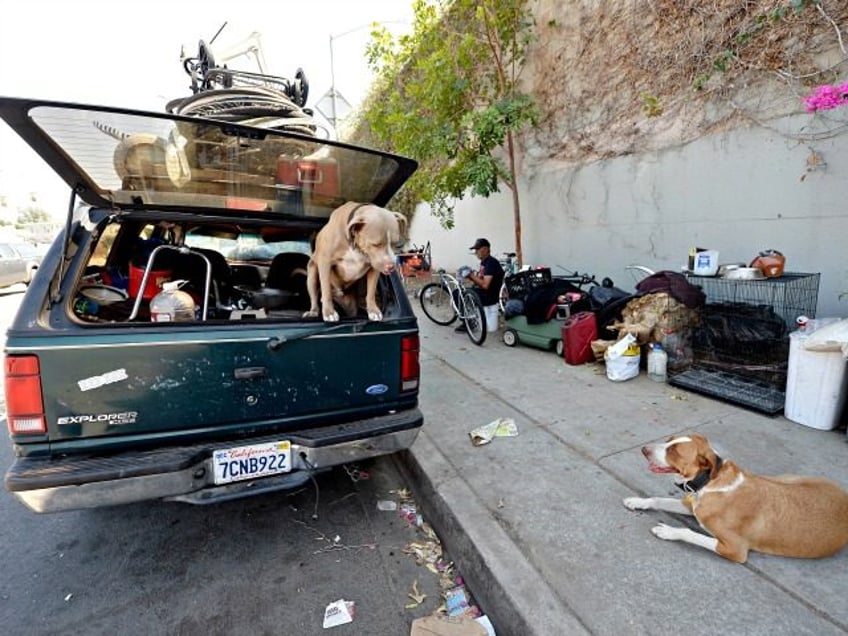 LOS ANGELES, CA - SEPTEMBER 23: A homeless man for over 30 years who lives inside his car repairs a bicycle as his dog Honey and neighbor's dog Niko stand guard September 23, 2015, in the Hollywood section of Los Angeles, California. Mayor Eric Garcetti and City Council members declared …