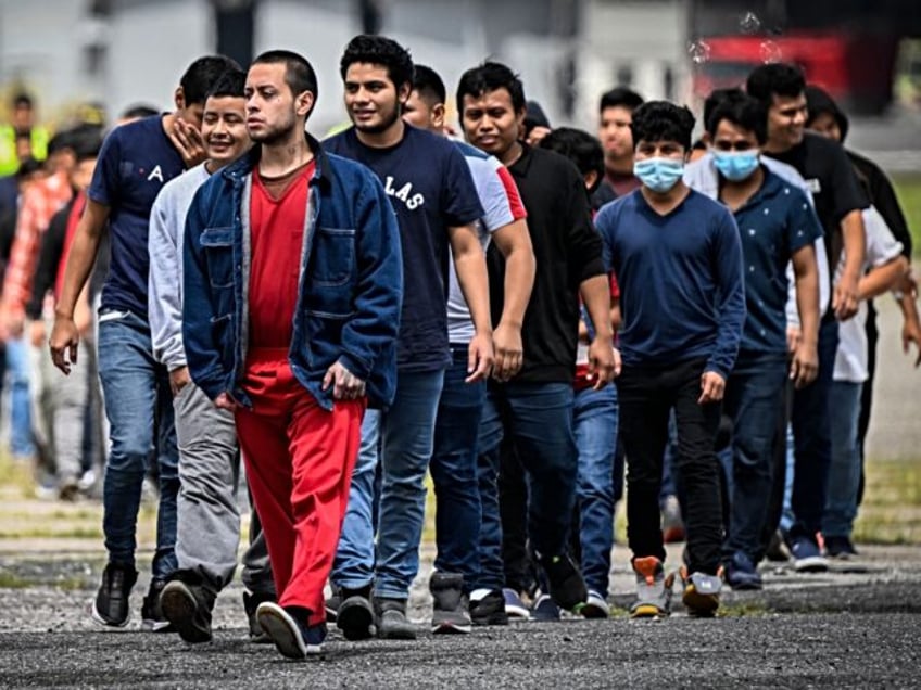 Guatemalan migrants deported from the United States walk on the airport runway upon their