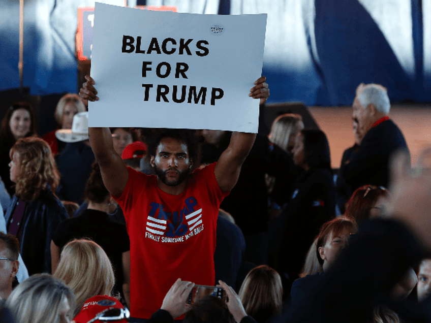 A man hold a "Blacks for Trump" sign as he waits to see US Republican presidential nominee