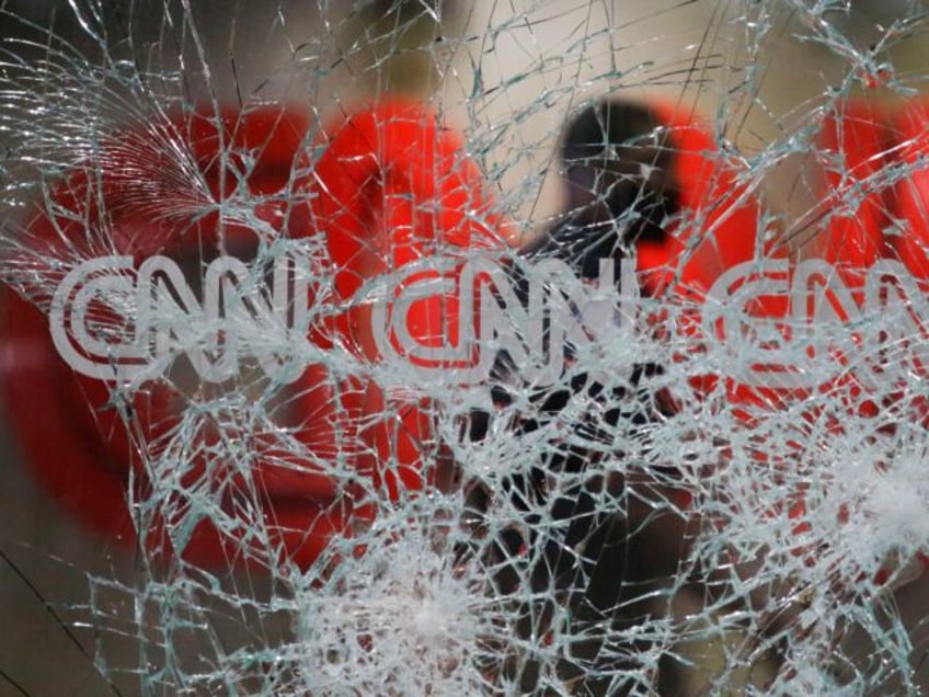 A security guard walks behind shattered glass at the CNN building at the CNN Center in the