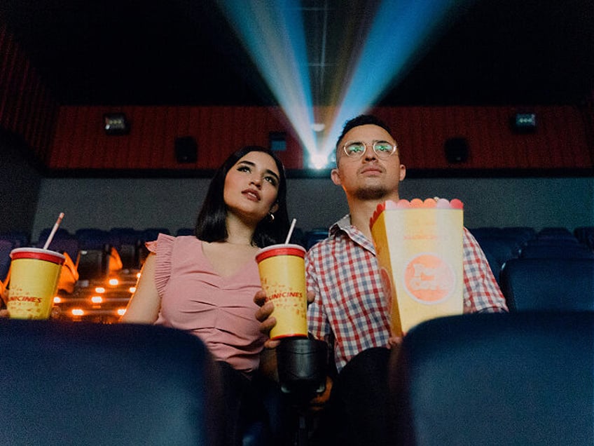 Couple at movie theatre with popcorn.