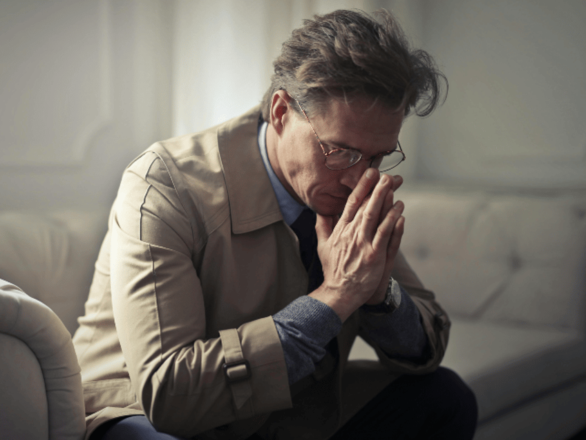Sad mature businessman thinking about problems in living room