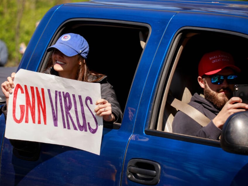 A woman holds a placard that seems to be calling the news...