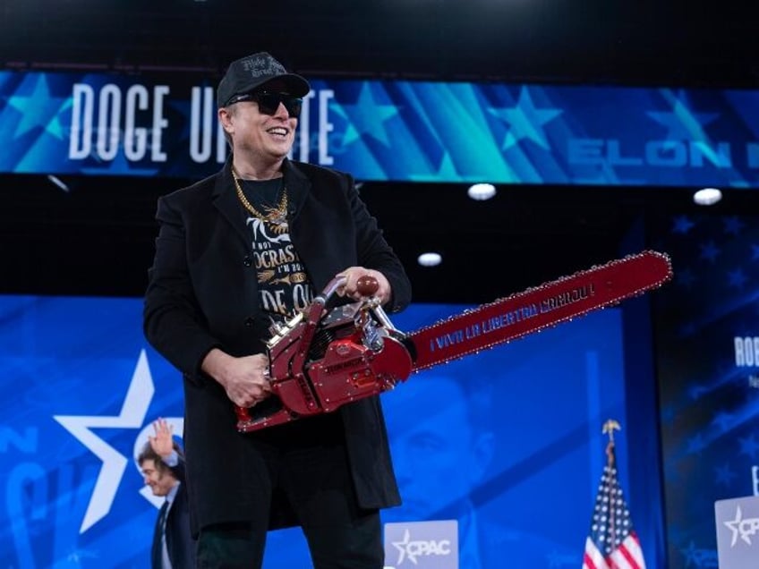 Elon Musk hold a chainsaw as he arrives to speak at the Conservative Political Action Conf