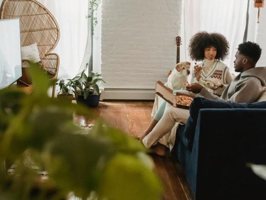 couple watching TV and eating pizza