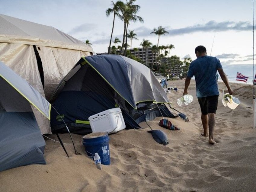 Carlos Lamas, a volunteer with Lahaina Strong, sets up lights for the tents at Fishing for