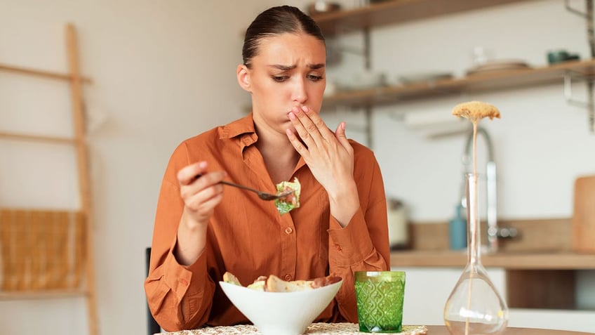 woman feeling nausea while eating a salad