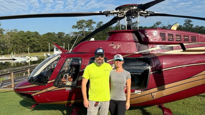 Zeb Hadley and a woman pose in front of Hadley's helicopter