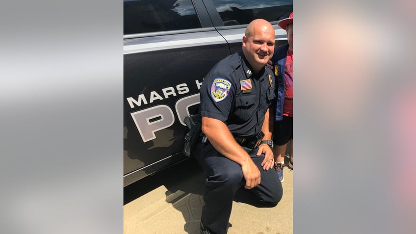 Chief Jon Clark poses next to a police car