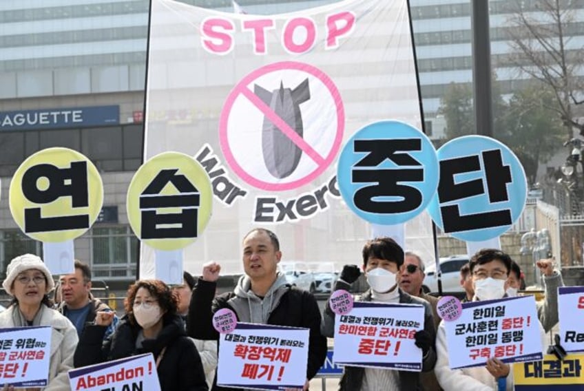 South Korean protesters hold banners that collectively read "Stop the military exercise be