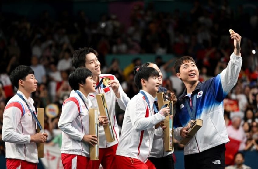 South Korea's Lim Jonghoon takes a selfie with his teammate and Chinese and North Korean m