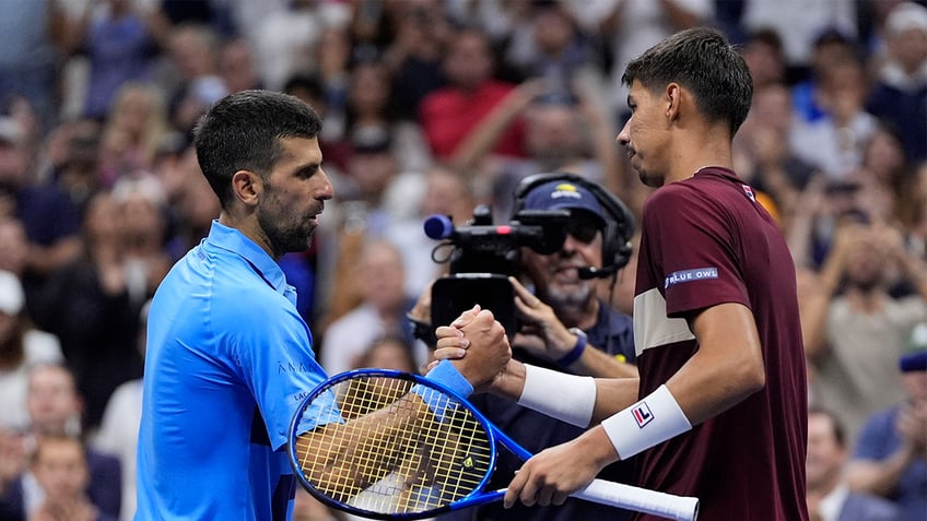 Novak Djokovic, of Serbia, shakes hands with Alexei Popyrin, of Australia