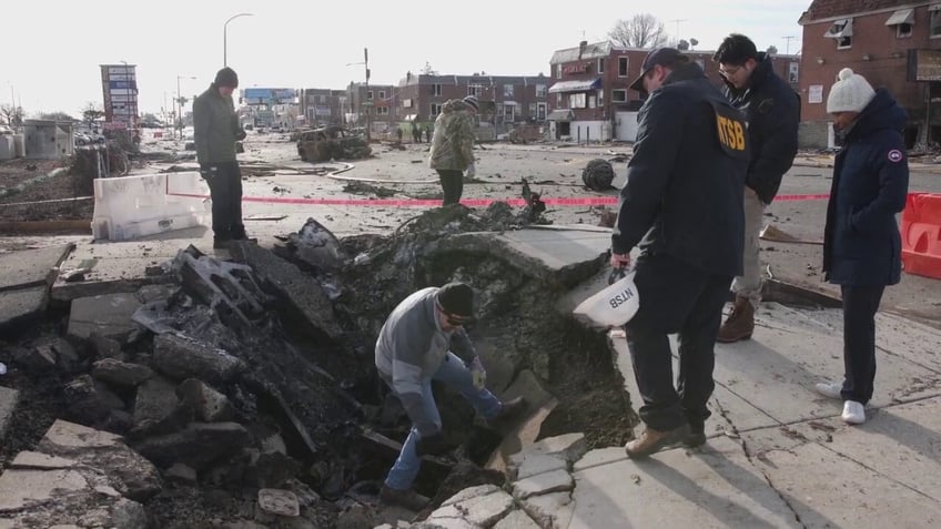 Officials standing in rubble