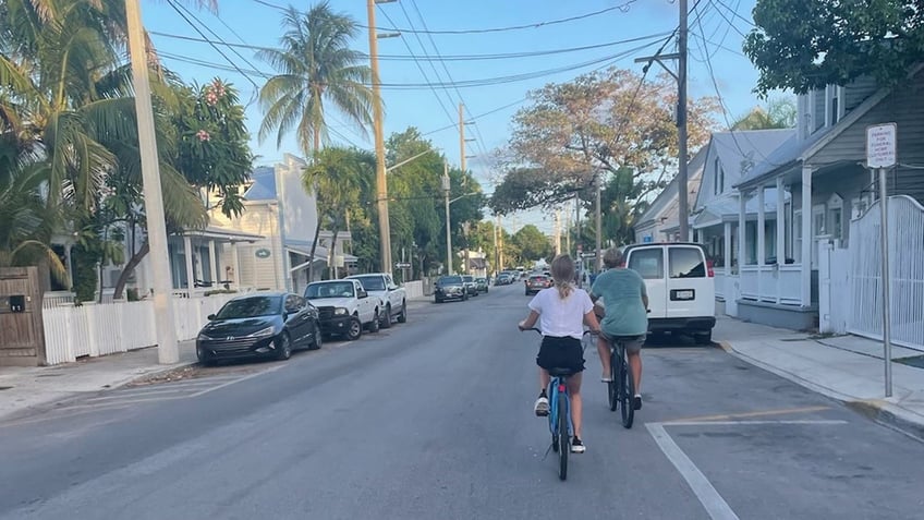 India Oxenberg riding a bike with her husband outdoors